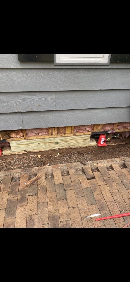 A brick sidewalk with some wood and red cans